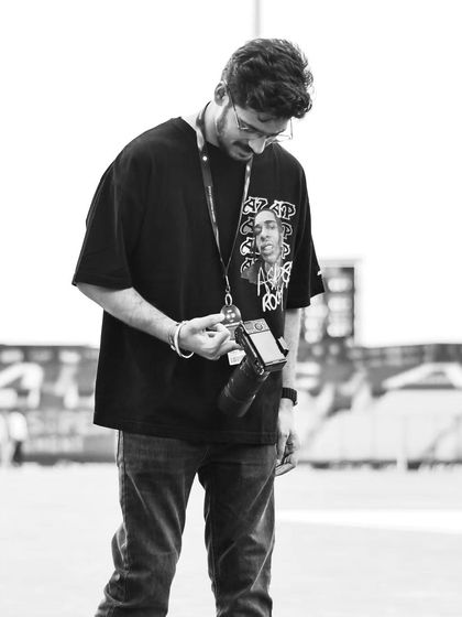 A candid, behind-the-scenes photo of me checking my camera settings on the field. I am always focused on getting the perfect shot.