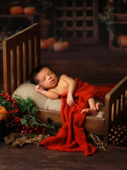 A wider shot of the miniature bed setup, showing the full scene with a rustic backdrop and seasonal props. This demonstrates how we build a complete, picturesque set for your baby.
