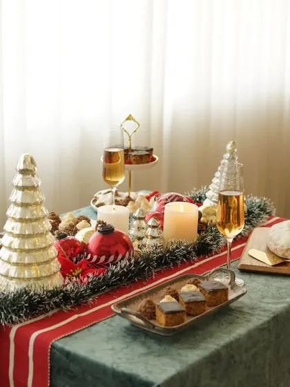 A beautifully decorated Christmas table spread, complete with a tree, candles, and a variety of festive bakes. This wide shot sets a magical holiday scene.