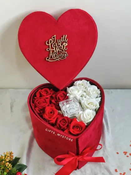 The top tier of the heart-shaped box, filled with red and white roses and a space for a special ring.