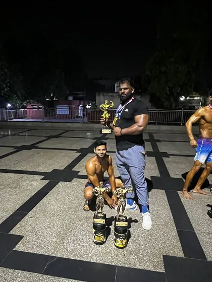 Posing with my champion and his trophies after a successful competition night. The hard work in the gym always pays off on the stage.