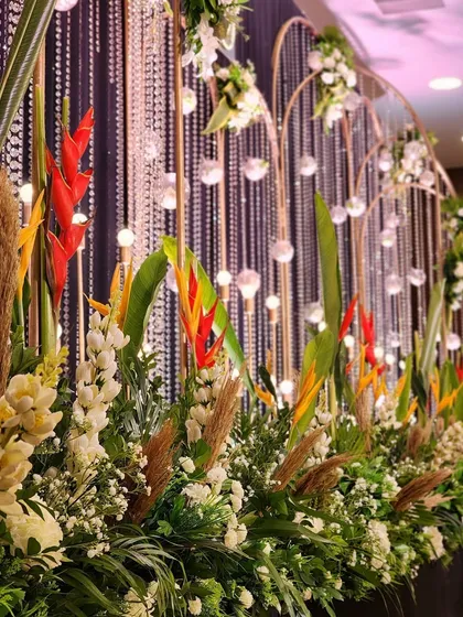 A close-up of the floral arrangements used in a bohemian-themed event, combining exotic flowers like birds of paradise with pampas grass and crystal hangings.