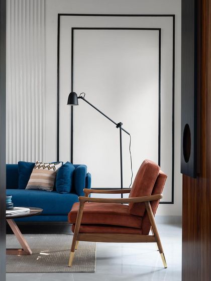 This living room uses a sophisticated grey palette, energized by a bold blue sofa and a terracotta-colored armchair. I used wall panels and trims to add texture and a sense of height, creating a contemporary space with a strong design language.