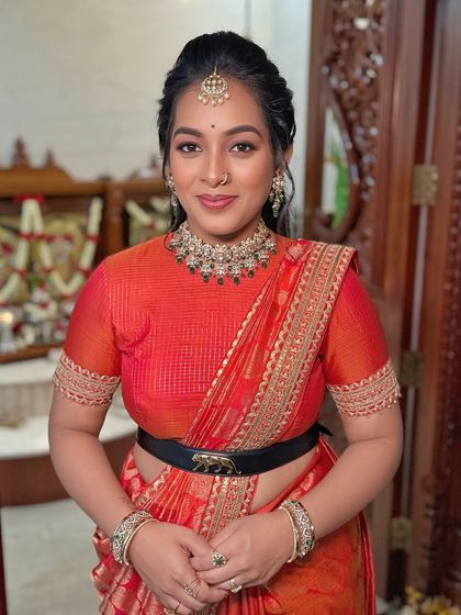 A cheerful bride in a modern Sabyasachi saree drape, featuring a unique belt that adds a contemporary twist to the traditional look.
