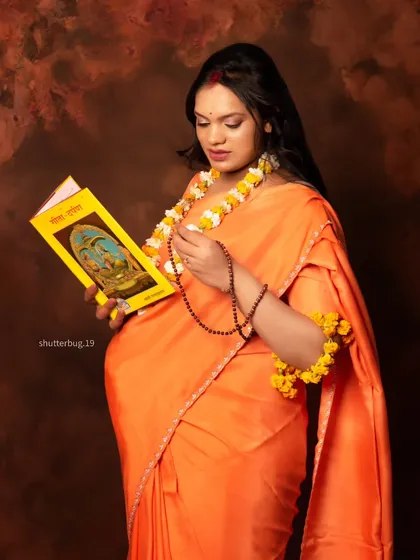 A solo portrait of the mom-to-be from the Ram Sita series. Dressed as Sita, she is seen reading a holy book, adorned with floral jewelry, capturing a moment of divine grace and motherhood.