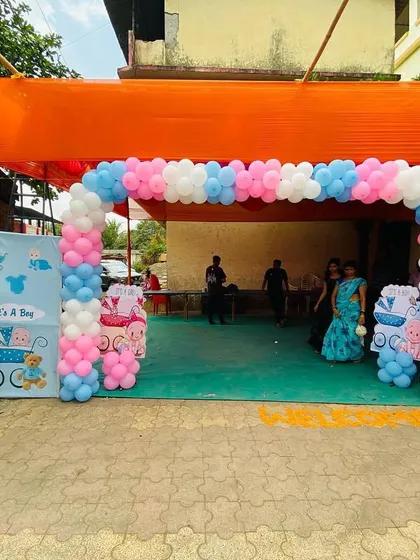 An outdoor entrance for a baby shower with a pink and blue balloon arch, perfect for a gender reveal party.