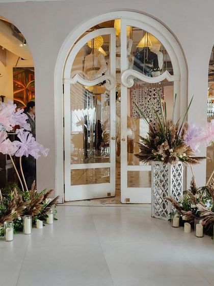 The entrance to the ring ceremony, decorated with large, whimsical fabric flowers and arrangements of pampas grass and candles, setting a dreamy and romantic tone.