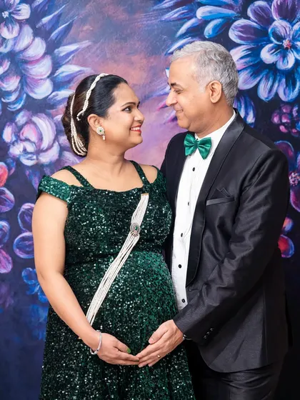 An elegant, formal portrait of a couple against a painted floral backdrop. Their classic attire and loving gaze make for a timeless image.