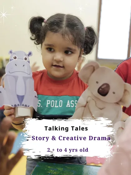 A young girl holds puppets, ready to tell a story. Our "Talking Tales" program for ages 2 to 4 uses props to spark imagination.