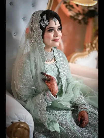 A portrait of the bride looking serene and elegant at her reception. The focus is on her beautiful smile and the intricate details of her mint green dress and jewelry.