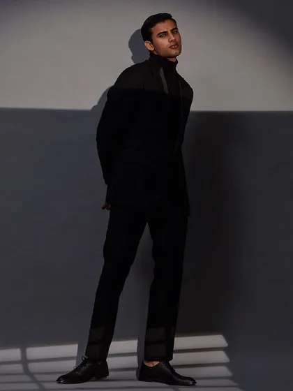 Shadow and light play across this dark, textured ensemble, highlighting the importance of fit and form in creating a memorable look.