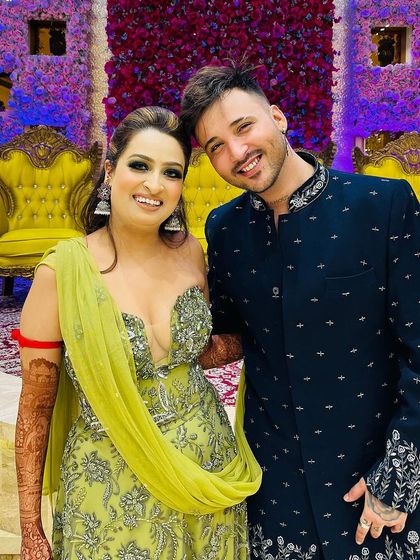 A client celebrating at a wedding in our navy blue Indo-Western jacket. The piece features silver embroidery on the collar and hem, adding a touch of festive sparkle.