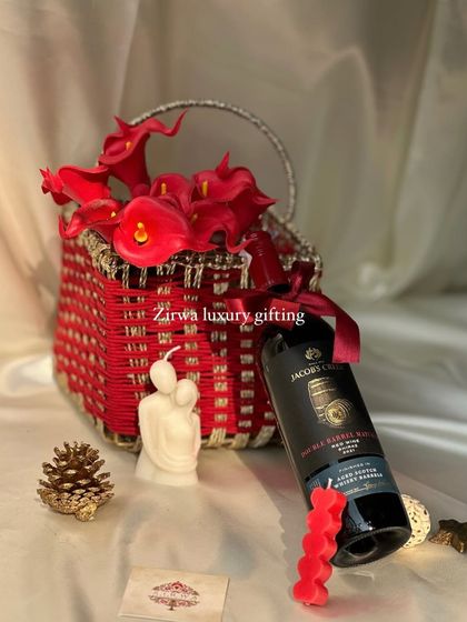 The Christmas season is here! This red-themed wine hamper, featuring a bottle of red wine, a romantic candle, and bright red flowers in a woven basket, is perfect for holiday gifting.