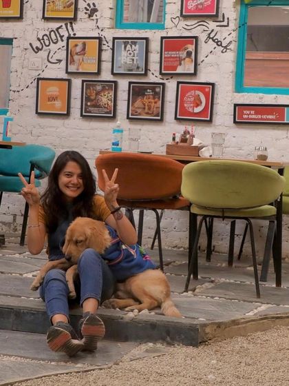 Peace, love, and dogs. A guest poses with a happy golden retriever, capturing the chill vibe of our cafe.