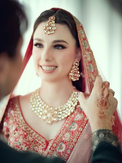 A close-up shot of the groom adjusting the bride's veil, a tender and caring gesture captured during a multicultural wedding in Germany.