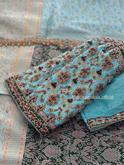 A light blue blouse with heavy, multi-color floral embroidery.