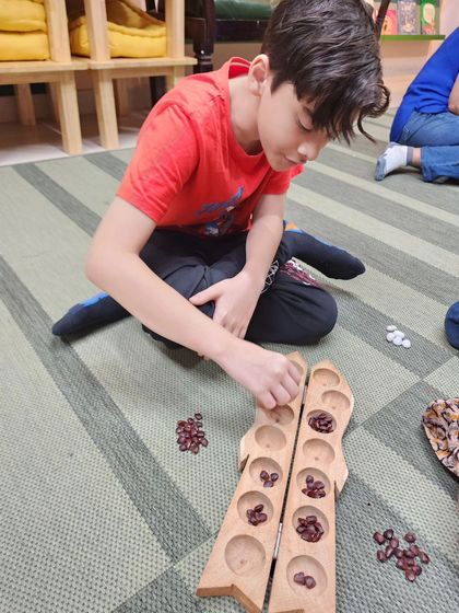 A young boy deeply focused on the Pallanguzhi board game. These sessions provide a wonderful opportunity for children to learn games that have been passed down through generations.
