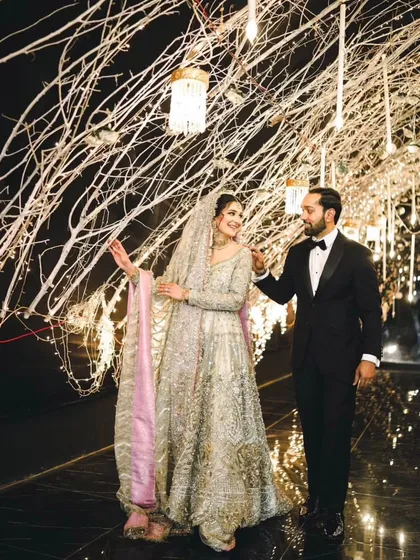 A candid shot of the couple walking through their beautifully decorated reception venue. Their interaction feels natural and full of love.