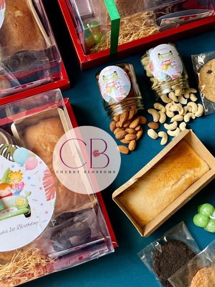 A complete look at our jungle-themed first birthday return favours. The hamper box includes jars of cashews and almonds, a tea cake, cookies, assorted chocolates, and a mini bubble candle.