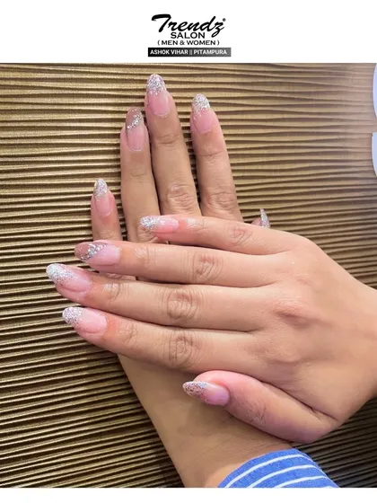 Here is another take on the classic glitter tip. These almond-shaped extensions have a sheer pink base that fades into a dense silver glitter at the ends, creating a chic and sparkling look.