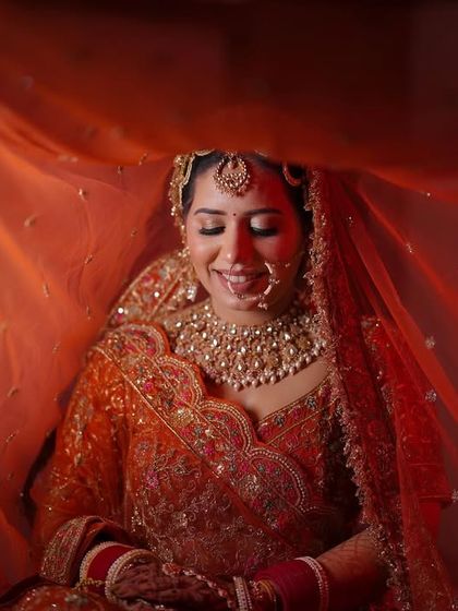 A serene bridal portrait under a flowing orange veil, creating a soft and dreamy atmosphere.