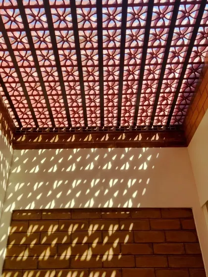I use architecture to paint with light. A terracotta jaali screen acts as a porous ceiling, casting intricate patterns of light and shadow that shift throughout the day, turning a simple room into a dynamic and living space.
