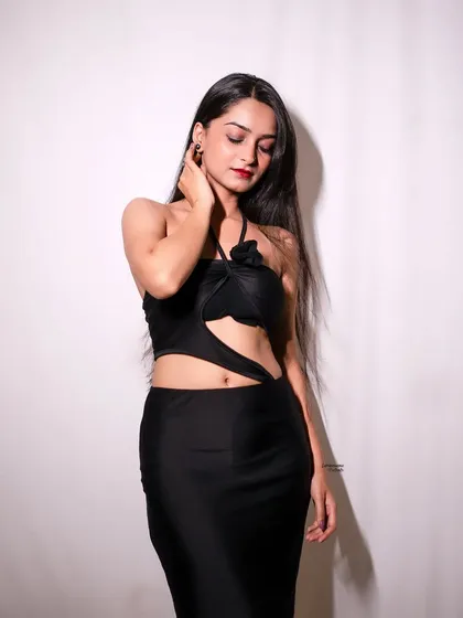 A soft and elegant pose, with the model looking down, highlighting the unique design of her black halter-neck dress.