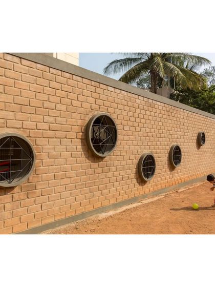 A toddler interacts with the circular windows along a boundary wall at Buddhi School. We use simple, playful architectural details like these to engage children's curiosity and create a stimulating environment.