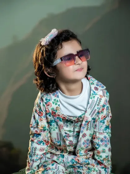 A cool and stylish kid's portrait with sunglasses and a floral outfit, set against a hazy mountain backdrop. This shows a more modern and fashionable approach to children's photography.