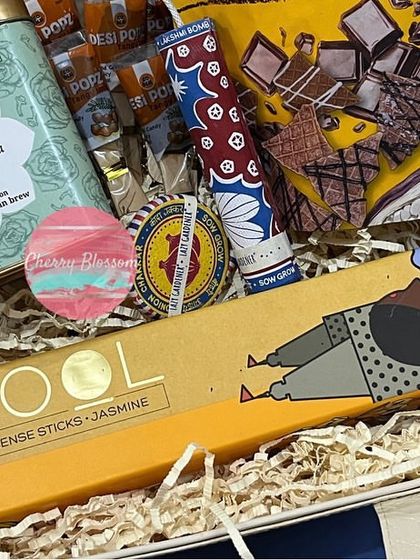 A close-up of our gourmet Diwali snack hamper. It features premium items like Phool jasmine incense sticks, Isvaari Kashmiri Kahwa tea, and Go Desi imli pops.