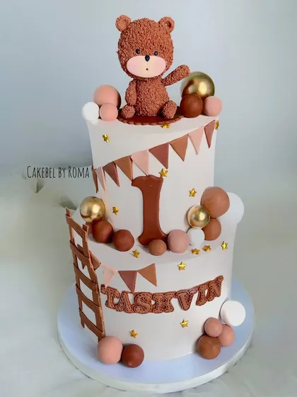 A charming two-tier woodland teddy bear cake for Tashvin's first birthday. The neutral brown and beige tones, along with the cute bear topper, create a warm and rustic feel.