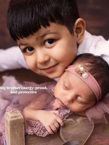 Big brother energy: proud and protective. This pose, with an older sibling looking over their new baby sister, is a simple and heartwarming way to capture their new relationship.