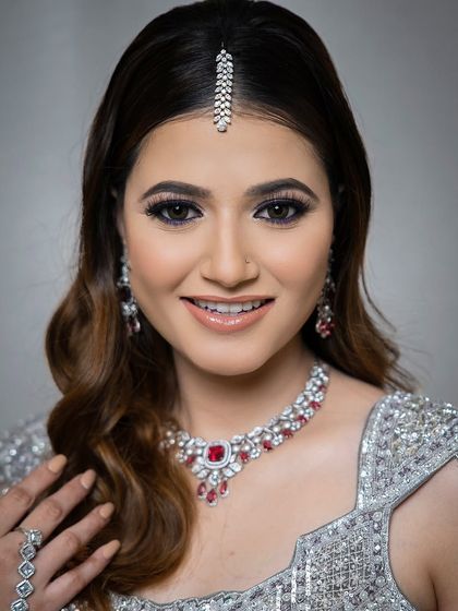 A close-up of the smiling model, her ruby necklace and maang tikka perfectly framing her face.