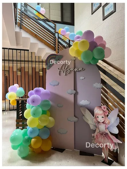 A sweet and simple backdrop with pastel balloons and a fairy cutout, perfect for a smaller, more intimate rainbow-themed celebration.