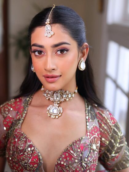 A close-up of a fresh and youthful pre-wedding look. The makeup features soft pink eyeshadow, a clean winged liner, and glowing skin, perfect for a sangeet or engagement ceremony.