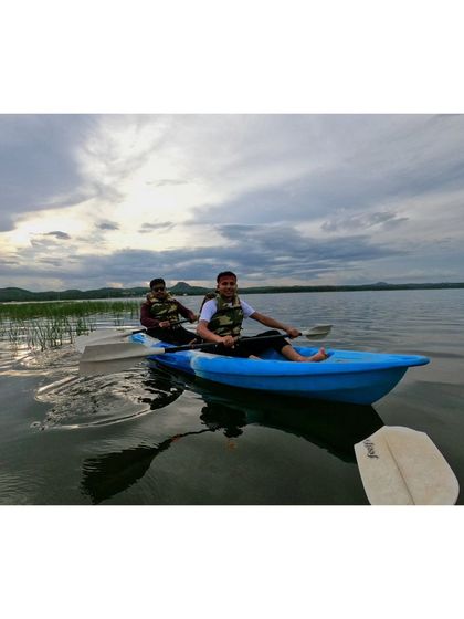 Friends enjoying a kayaking adventure, with the vast water and distant hills creating a beautiful backdrop.