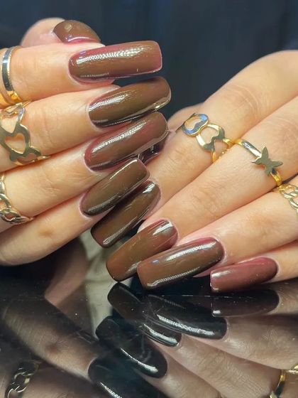 A deep, chocolate brown cat-eye polish on long, square-shaped nails.