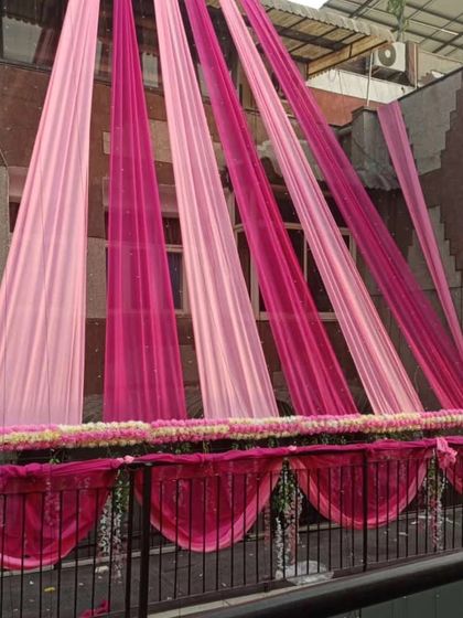 Elegant pink-themed draping for a home's balcony and exterior. This design uses shades of pink fabric and a floral border for a sophisticated look.