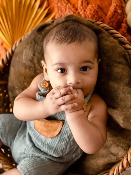 A shy and sweet moment. This baby is curiously peeking at the camera while nibbling on his hands, a classic baby mannerism.