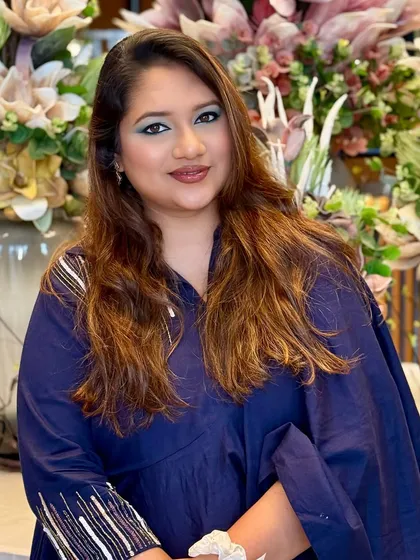 A full view of the client, her bold eye makeup complementing her simple, chic outfit.
