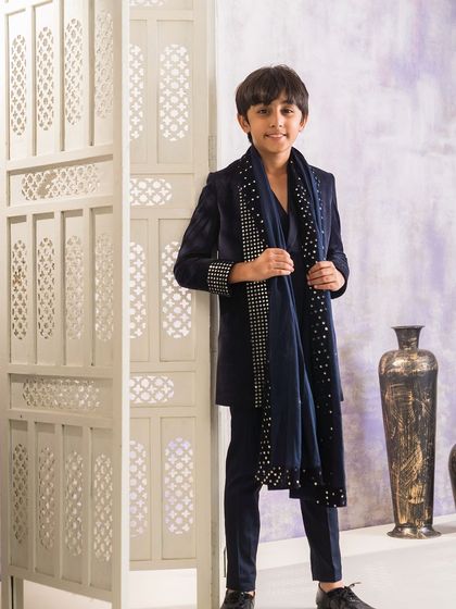 This is a complete Indo-western look featuring a navy blue long jacket made from velvet. The jacket and matching dupatta are embellished with lines of silver studs for a striking effect.