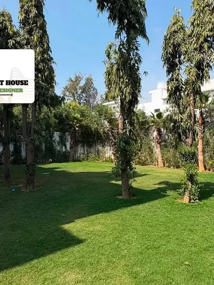 This image highlights the large, open lawn space bordered by mature trees, providing a sense of privacy and a beautiful natural backdrop for this residential property.
