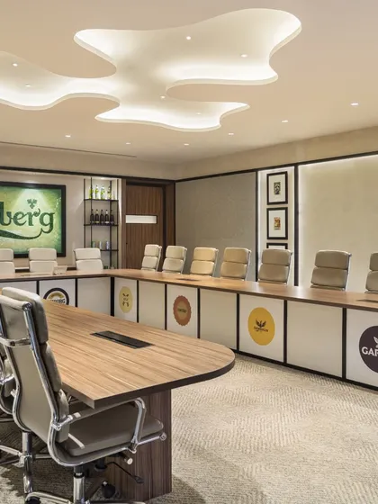 The final, realized boardroom at the Carlsberg office. This image shows the successful execution of the design concept, from the custom lighting fixture to the branded table and memorabilia displays.