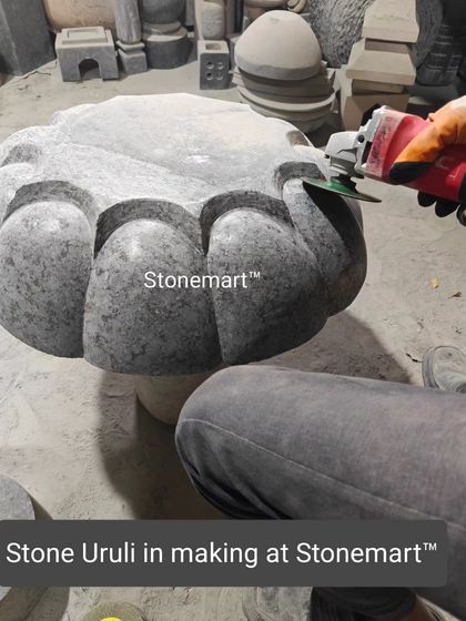 A glimpse into our workshop, where a granite uruli birdbath is being hand-finished by one of our skilled artisans. The grinding process reveals the stone's natural texture and beauty.