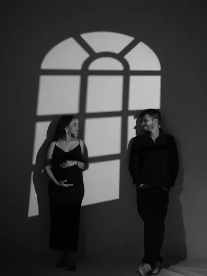 This wide shot shows the couple standing apart but connected by their gaze, with the window shadow between them. It’s an artistic, minimalist composition that speaks to their individual strength and shared journey.