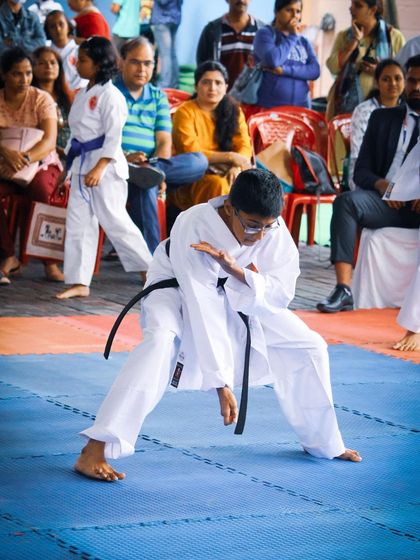 Performing Kata in front of an audience builds confidence and sharpens focus. A student demonstrates his form during a public event, showcasing the poise and concentration developed through his training.