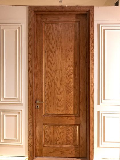 This crown-cut ashwood veneer door features a subtle metal inlay and a two-panel design, which helps to elongate the appearance of a 9-foot doorway.