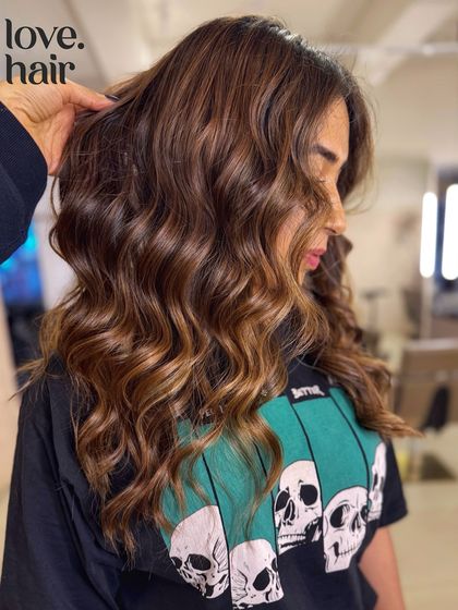 A side view of the 'brown butter almond' balayage, showing how the colour complements the client's features and the soft, wavy style.