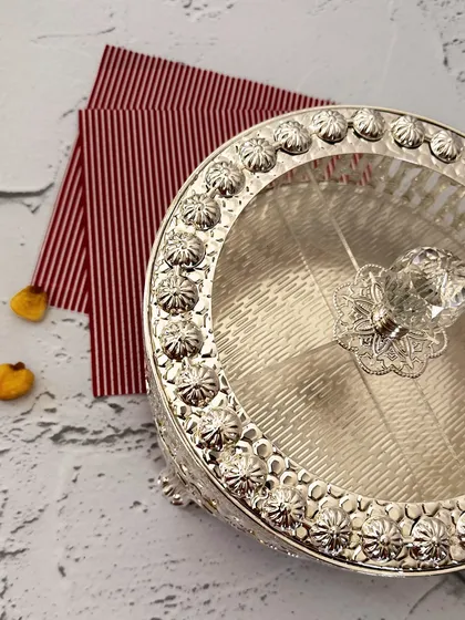 A keepsake box that does more than hold, it delights. This ornate silver-plated piece with a crystal knob is perfect for dry fruits, sweets, or little festive treasures.