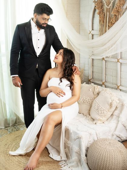 The loving gaze between partners tells a beautiful story. This studio shot, with its bohemian-inspired decor, creates a warm and intimate atmosphere for a couple's maternity session.